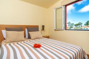 Un dormitorio con una cama con una flor roja. en 2 bedrooms appartement with shared pool furnished terrace and wifi at Prazeres 5 km away from the beach, en Campanário