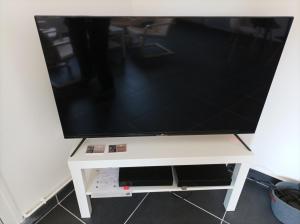 uma televisão de ecrã plano sentada numa bancada de televisão branca em O'Couvent - Appartement 80m2 - 2 chambres - A331 em Salins-les-Bains