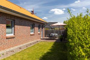 ein Backsteinhaus mit einer Terrasse mit einem Sonnenschirm in der Unterkunft Ferienhaus Südheide in Hermannsburg