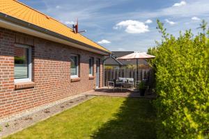 a brick house with a patio with an umbrella at Ferienhaus Südheide in Hermannsburg