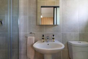 a bathroom with a sink and a toilet and a mirror at Alimama Spaces: Nonku's Greenlee Studio in Sandown +21 photos