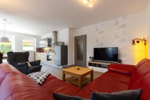 ein Wohnzimmer mit einem roten Sofa und einem TV in der Unterkunft Ferienhaus Südheide in Hermannsburg