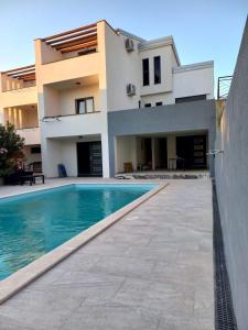 a house with a swimming pool in front of a house at Apartments STAR with Pool in Biograd na Moru