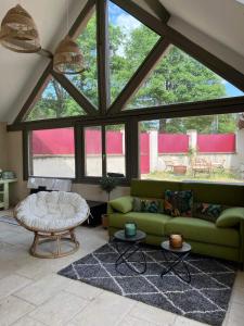 a living room with a green couch and a large window at Une pause s'impose ;) in Méry-sur-Cher