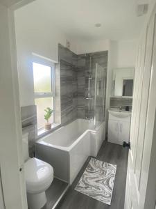 ein Badezimmer mit einer Badewanne, einem WC und einem Waschbecken in der Unterkunft Quay Cottage in Parkgate