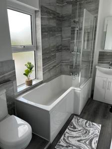 ein Badezimmer mit einer Badewanne, einem WC und einem Waschbecken in der Unterkunft Quay Cottage in Parkgate