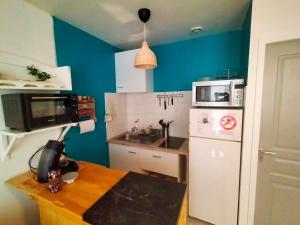 cocina pequeña con paredes azules y nevera blanca en Le Mistral location, en La Ciotat