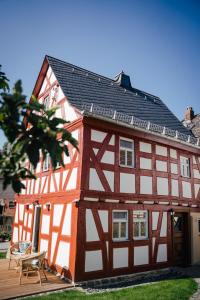 ein rot-weißes Gebäude mit einer Holzterrasse in der Unterkunft Fachwerkhaus in Rettert