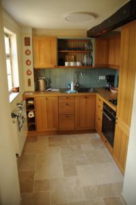 uma cozinha com armários de madeira e piso em azulejo em Fachwerkhaus em Rettert