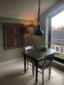 a dining room with a table and chairs and a window at Bij van der Veer in Julianadorp