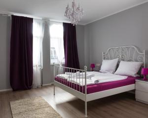 Un dormitorio con una cama blanca con sábanas moradas y una lámpara de araña. en Hotel Forty Four en Frankfurt