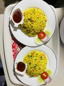 dos platos de comida con espaguetis y tomates. en Janas Blue Water Corner en Trincomalee