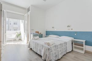 a white bedroom with a bed and a blue wall at Hotel Lucerna in Cesenatico