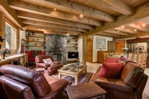 a living room with leather furniture and a stone fireplace at Chalet Ecritoire - Alpes Travel - Les Houches - Sleeps 10 in Les Houches