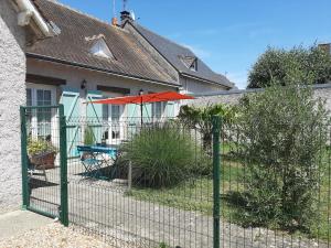 a fence in front of a house with an umbrella at Les deux anes in Veuves