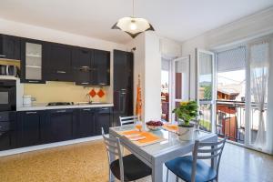 una cucina con armadi neri e tavolo con sedie di Iris Apartment Lago Maggiore ad Angera