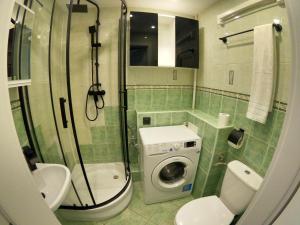 a bathroom with a shower and a washing machine at Faryna Apartament in Ruciane-Nida