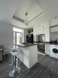 a white kitchen with a counter and stools in it at 2 bed sleeps 6 Beach retreat St Annes on sea in Lytham St Annes
