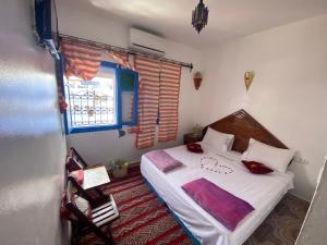 a bedroom with a bed with white sheets and a window at Riad sakura in Chefchaouene