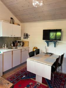 a kitchen with a table and a tv on the wall at Skagen hytte in Skagen