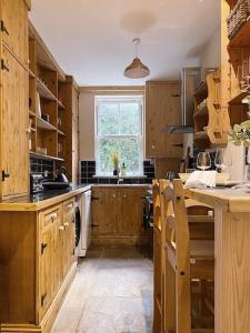a large kitchen with wooden cabinets and a window at Beautiful & cosy 4 bedroom home in Todmorden