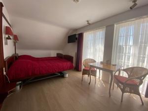 Schlafzimmer mit einem roten Bett, einem Tisch und Stühlen in der Unterkunft Vakantiecentrum Zeelinde in De Haan