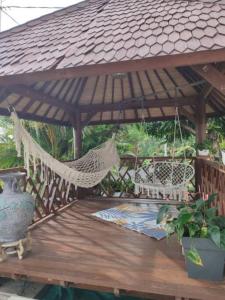 a hammock on a wooden deck with a gazebo at Entre Terre & Mer (Sainte rose)974 in Sainte-Rose