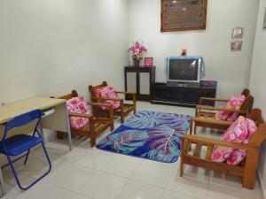 a room with chairs and a table and a tv at Homestay Intan Payung Bukit Katil Tuah Perdana in Malacca