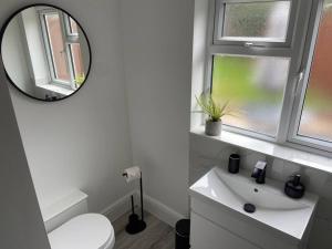 Baño blanco con espejo y lavabo en Modern Ground Floor Garden Apartment With Parking, en South Hayling