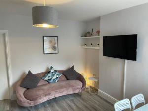 een woonkamer met een bank en een flatscreen-tv bij Modern Ground Floor Garden Apartment With Parking in South Hayling