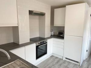a kitchen with white cabinets and a white refrigerator at Modern Ground Floor Garden Apartment With Parking in South Hayling