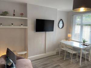 a living room with a table and a tv on the wall at Modern Ground Floor Garden Apartment With Parking in South Hayling