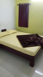 a bed in a bedroom with a brown blanket on it at Voyage Munnar Laya Home Stay in Suryanelli