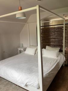 ein weißes Bett mit Baldachin in einem Schlafzimmer in der Unterkunft Rustig appartement in het groen met terras in Kontich