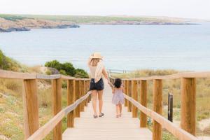 a woman and a little girl walking down a wooden bridge at Sol Parc Hotel & Apartments in Son Parc