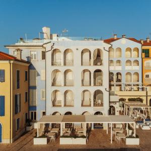 - un grand bâtiment blanc avec des tables et des chaises devant dans l'établissement Life Hotel Seaview & Spa, à Porto Recanati