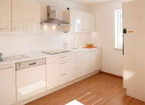 a white kitchen with white cabinets and a window at Ferienwohnung Baabe Kapitan Blaubar Ref. (Ref.189689-1) in Baabe +10 photos