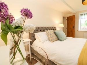 a bedroom with a bed with purple flowers in a vase at The Cottage, 5 Richley Terrace in Newcastle upon Tyne