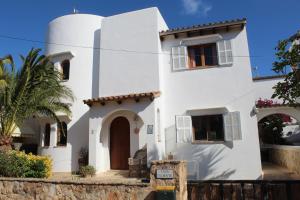 una casa blanca con un cartel delante en Casa Caliente, en Cala Santanyi