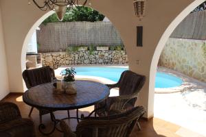 eine Terrasse mit einem Tisch und Stühlen sowie einem Pool in der Unterkunft Casa Caliente in Cala Santanyi