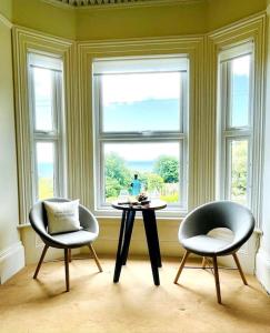 文特諾的住宿－Lottie's Lookout, Ventnor with fantastic Sea Views，窗户前设有2把椅子和1张桌子的房间