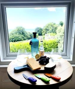 einen Holztisch mit einer Flasche und einem Fenster in der Unterkunft Lottie's Lookout, Ventnor with fantastic Sea Views in Ventnor
