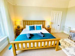 ein Schlafzimmer mit einem großen Holzbett mit blauen Kissen in der Unterkunft Lottie's Lookout, Ventnor with fantastic Sea Views in Ventnor