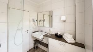 Baño blanco con lavabo y espejo en Europa Hotel Kühlungsborn en Kühlungsborn