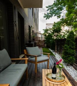 a patio with two chairs and a table with a bottle of wine at GREEN CORNER Apartment in Bucharest