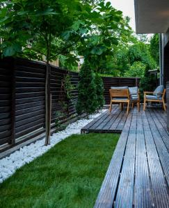 a backyard with a wooden deck with chairs and a table at GREEN CORNER Apartment in Bucharest