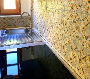 a kitchen with a sink and a tiled wall at Mont2roux in Montpeyroux