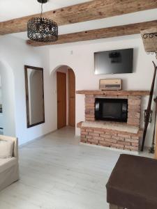 a living room with a tv and a brick fireplace at Patak28 Apartmanok in Sopron
