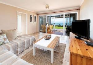 a living room with a couch and a flat screen tv at 82 De Bakke Terrace in Mossel Bay