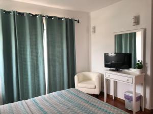 a bedroom with a bed and a tv and a chair at Casa GiGi in Sagres